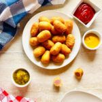 air fryer mini corn dogs on a plate next to ketchup and mustard