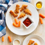 air fryer dino nuggets on a plate with carrots and dipping sauce