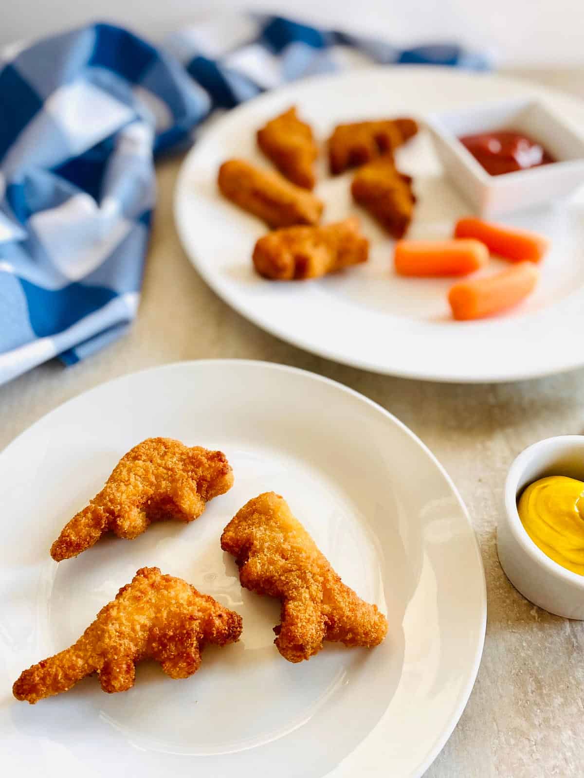 air fryer dinosaur nuggets on a plate with carrots and dipping sauce