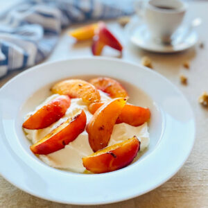 air fryer nectarines in a bowl with yogurt and granola with coffee in the background