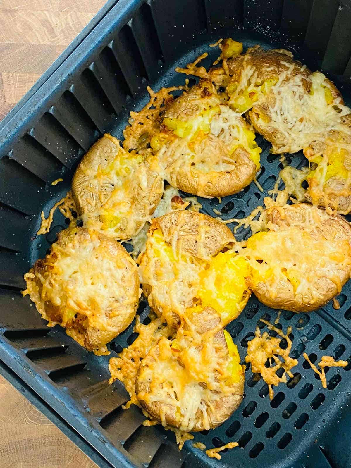 air fryer smashed potatoes in air fryer basket topped with garlic parmesan