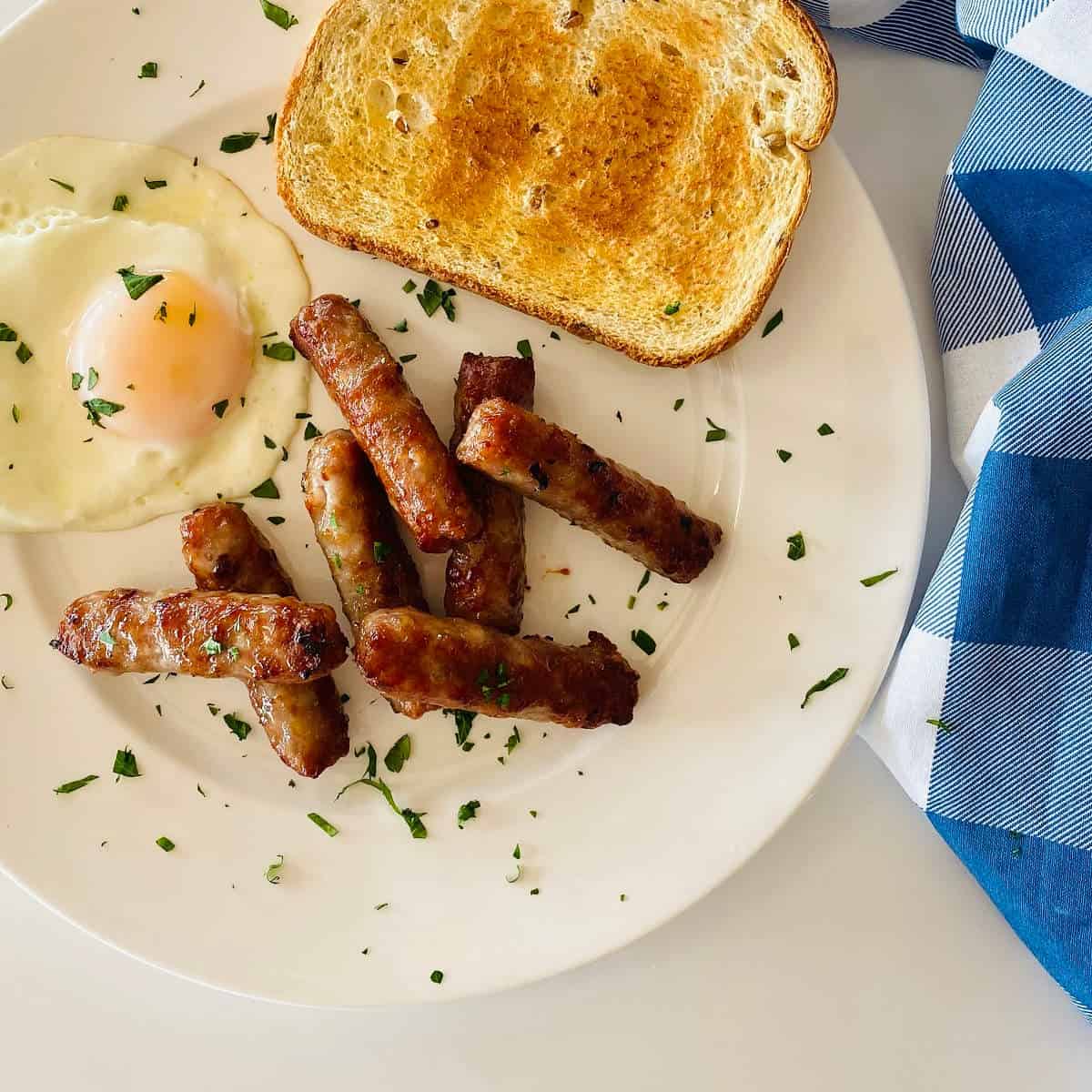 breakfast sausage links cooked in air fryer on plate with eggs and toast