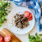 chuck roast air fryer sliced on a plate with tomato and parsley garnish