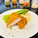 air fryer shake and bake pork chops on a plate with asparagus and macaroni salad and spices in the background