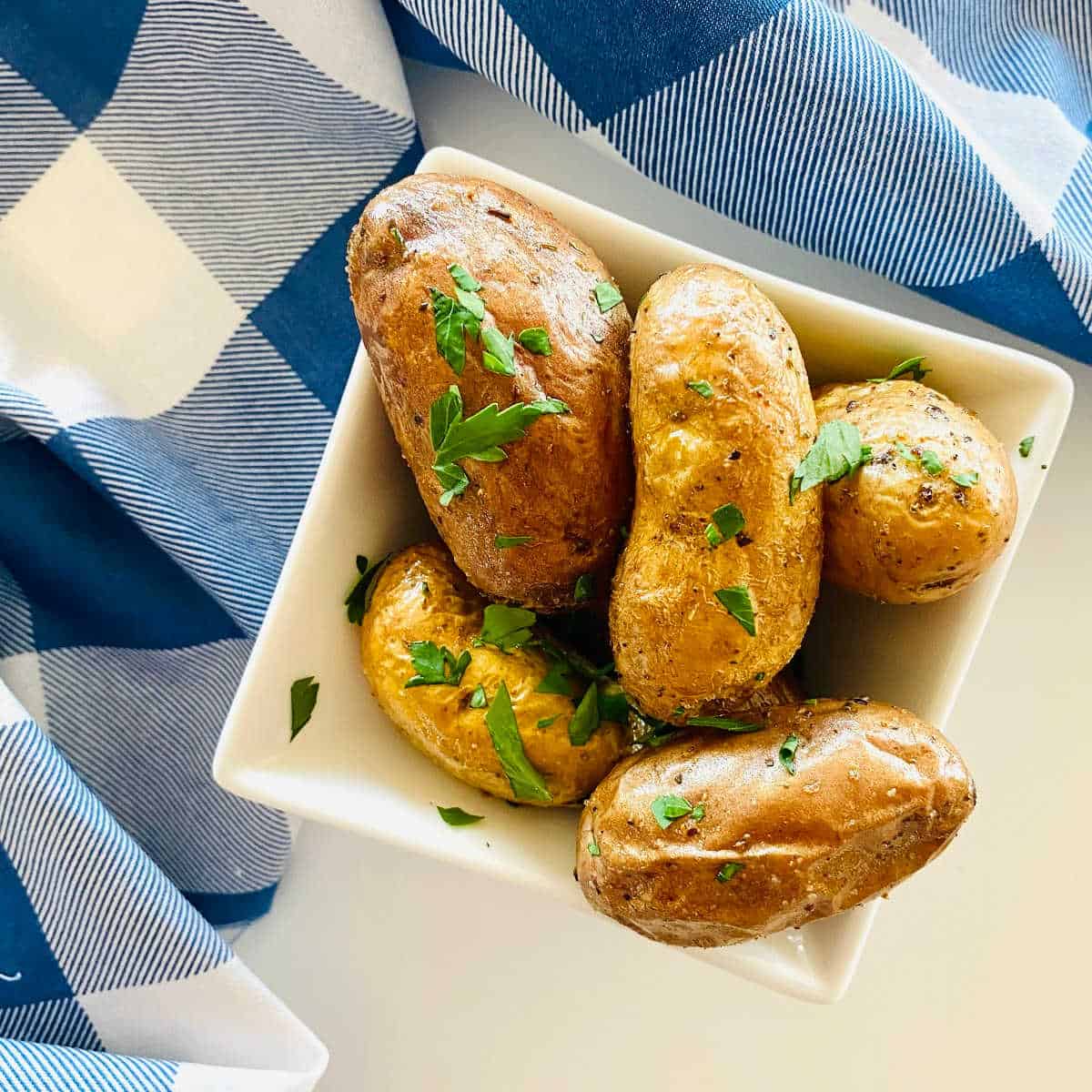 air fryer fingerling potatoes in a dish garnished with parsley.